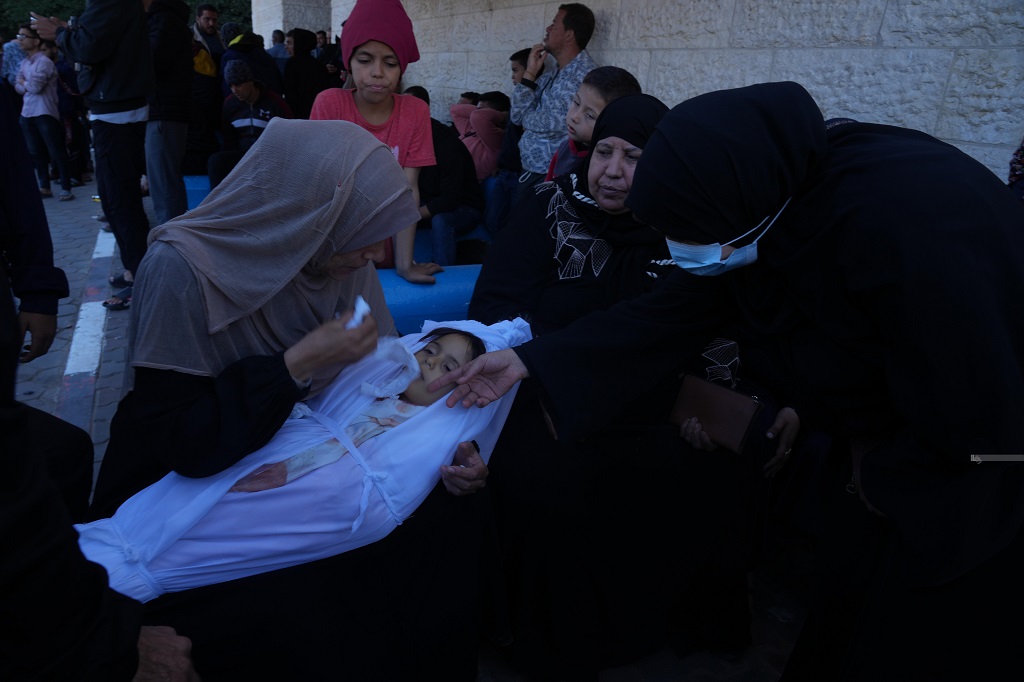 مواطنات يودعن طفلة ارتقت جراء القصف الإسرائيلي على منازل المواطنين في دير البلح وسط قطاع غزة (تصوير: حاتم موسى/وفا)